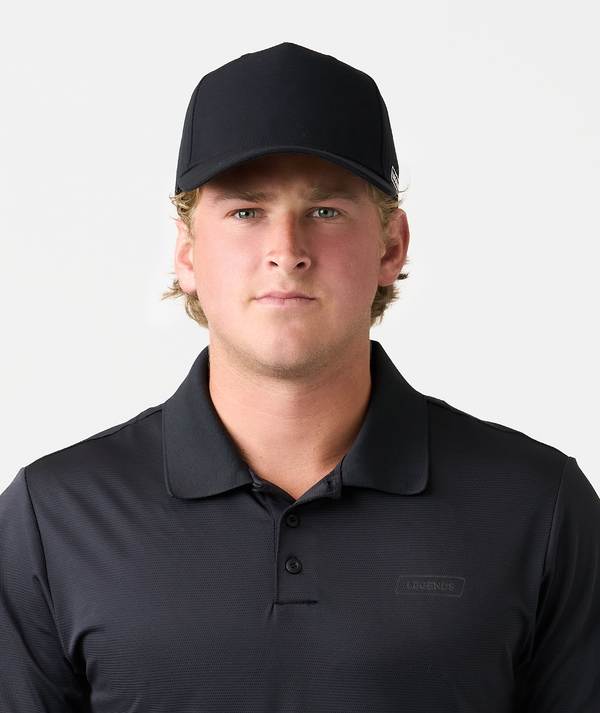 Black baseball cap with curved bill worn by model with blonde hair against neutral background.