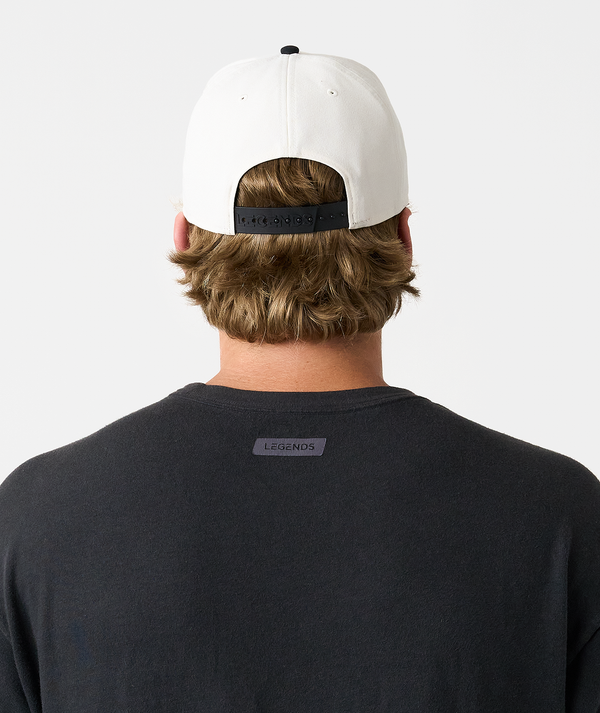 White baseball cap with black snapback closure worn on back of head.