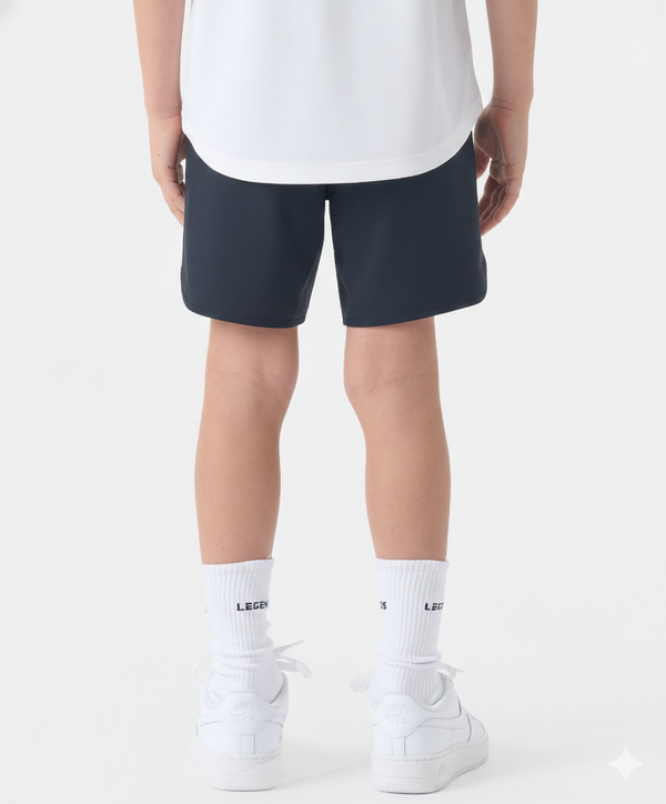 Child wearing black shorts with white socks and white sneakers.