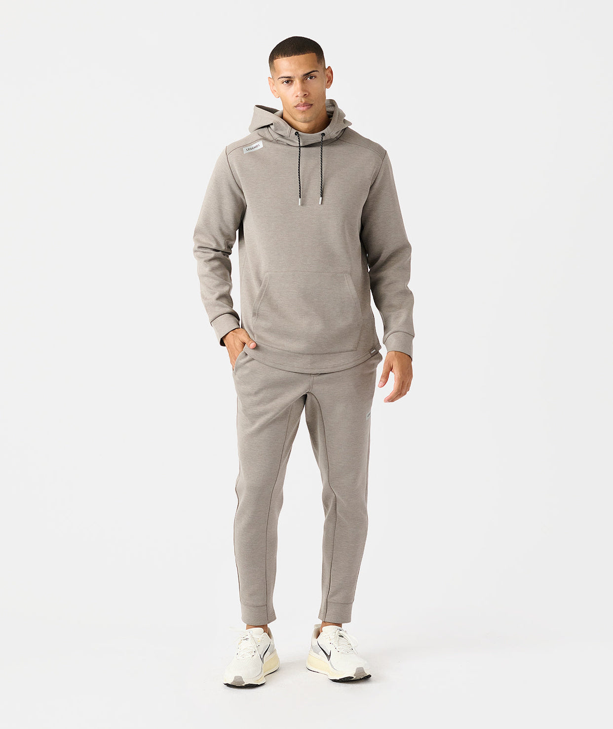 Man wearing taupe heather hoodie and matching joggers with drawstring waist and cuffed ankles.