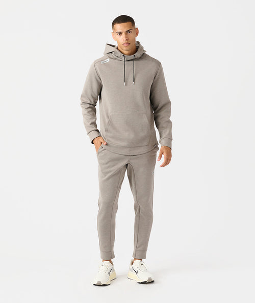 Man wearing taupe heather hoodie and matching joggers with drawstring waist and cuffed ankles.