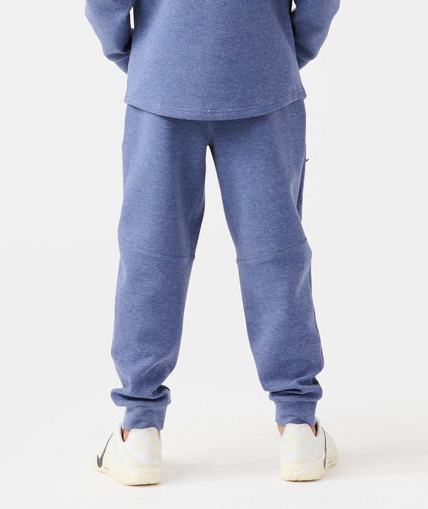 Child wearing heather blue pullover hoodie and matching joggers with cuffed ankles and white sneakers.