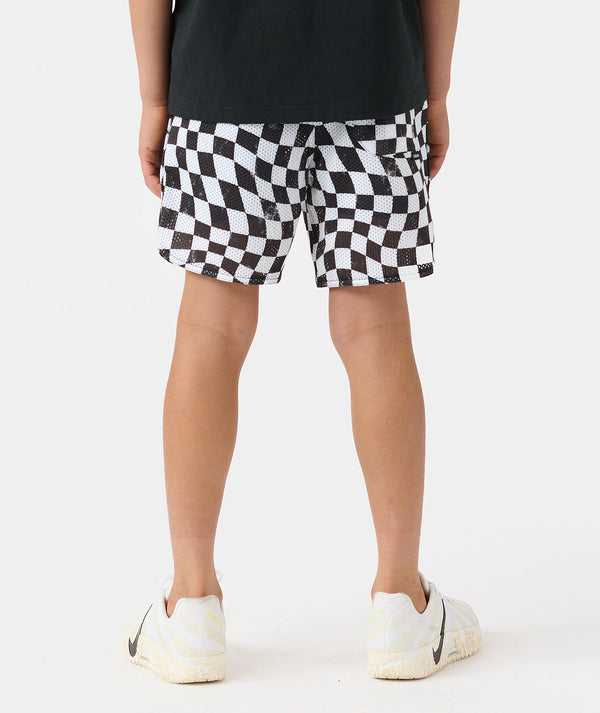 Child wearing black and white warped checkerboard mesh shorts with black shirt and white sneakers.