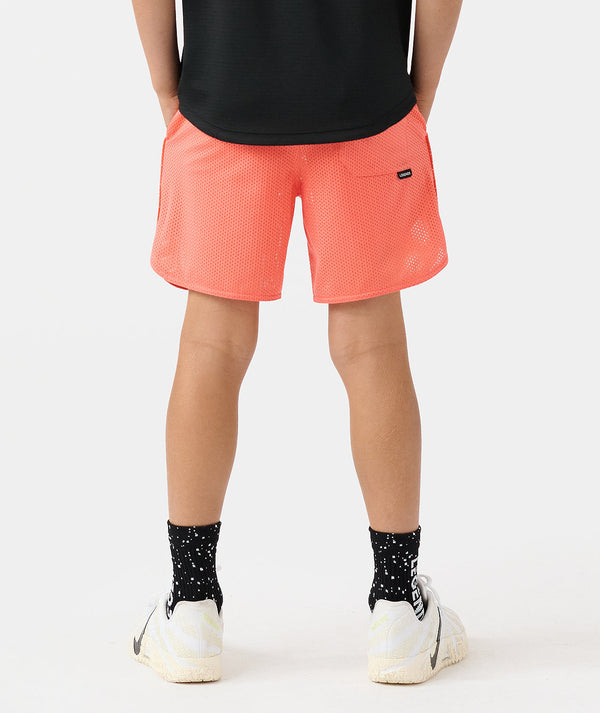 Coral mesh athletic shorts with small brand logo on hip, worn with black shirt and patterned socks.