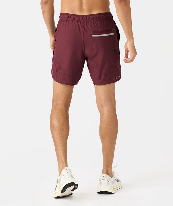 Burgundy athletic shorts with mesh paneling, back pocket, and reflective strip, worn with white running shoes.
