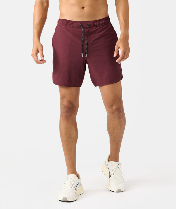 Burgundy shorts with drawstring waist and white sneakers on male model.