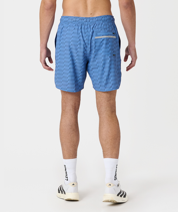 Blue athletic shorts with geometric rhombus pattern, elasticated waistband, and yellow trim detail on back pocket.