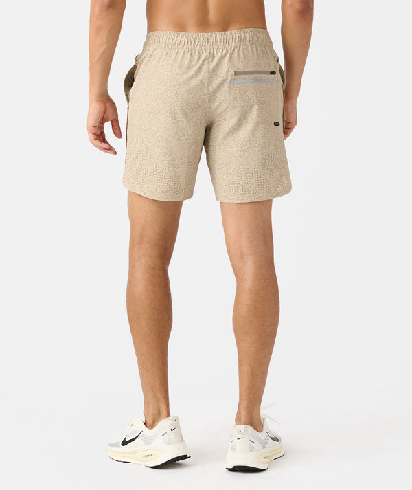 Man wearing beige textured shorts with back pocket, viewed from behind.