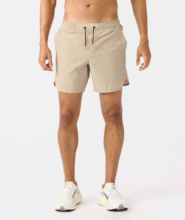 Beige heathered shorts with drawstring waist and side pockets on male model wearing white sneakers.