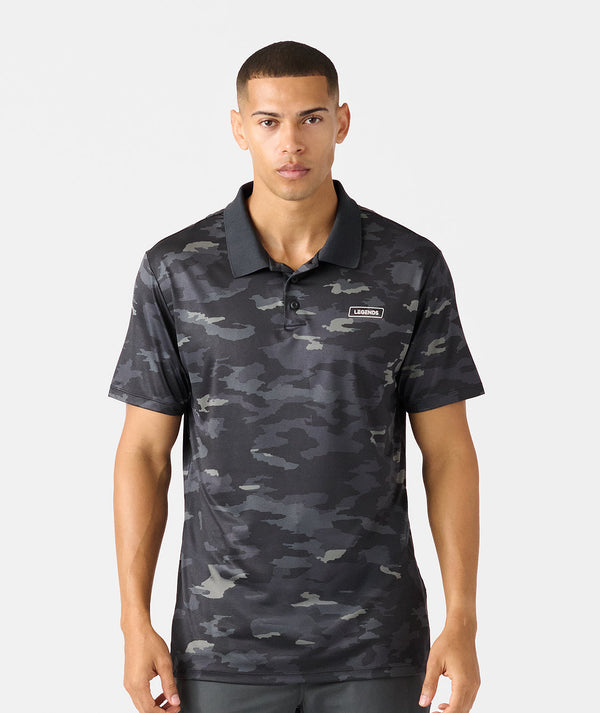 Black camouflage polo shirt with short sleeves, solid collar, and small branded chest patch.