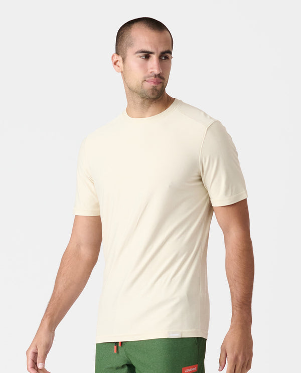 Cream-colored short-sleeve crewneck t-shirt on a man wearing green shorts.