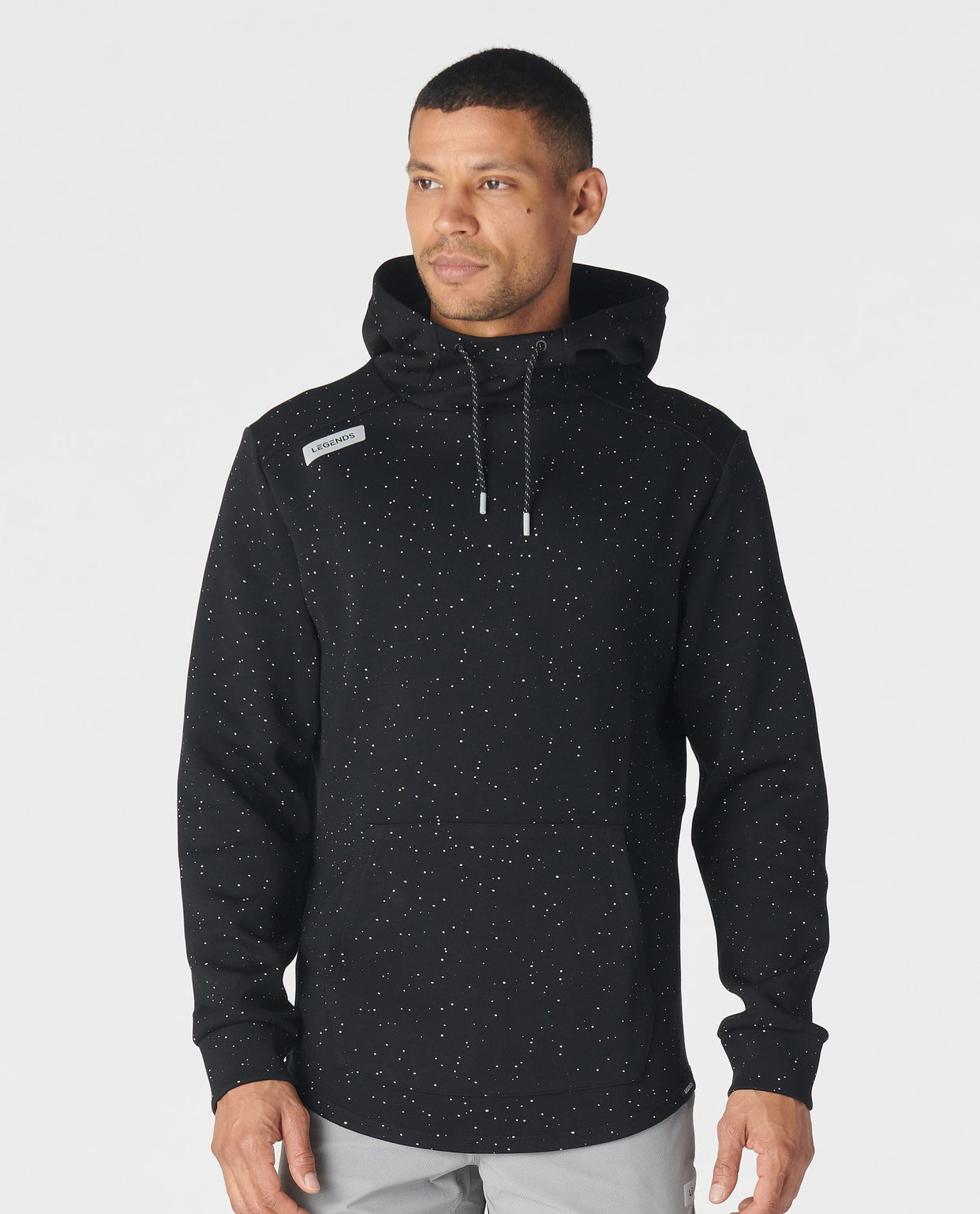 Black hoodie with white speckled splatter pattern throughout, drawstring hood, and brand label on chest.