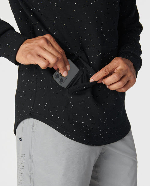 Black hoodie with white speckled pattern, front kangaroo pocket, worn with gray pants.
