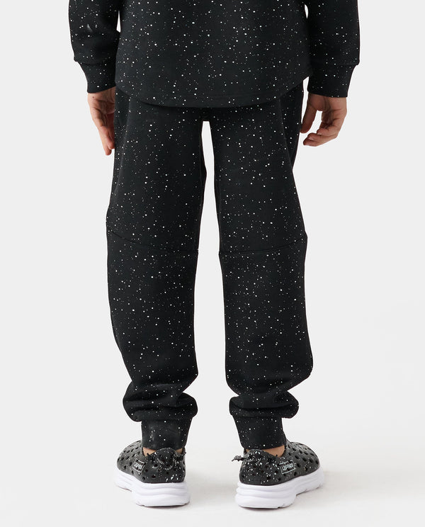 Black joggers with white splatter print throughout, shown from behind with ribbed cuffs.